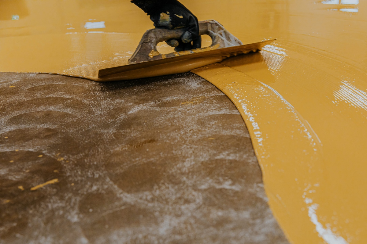 worker, coating floor with self leveling epoxy resin in industrial workshop.