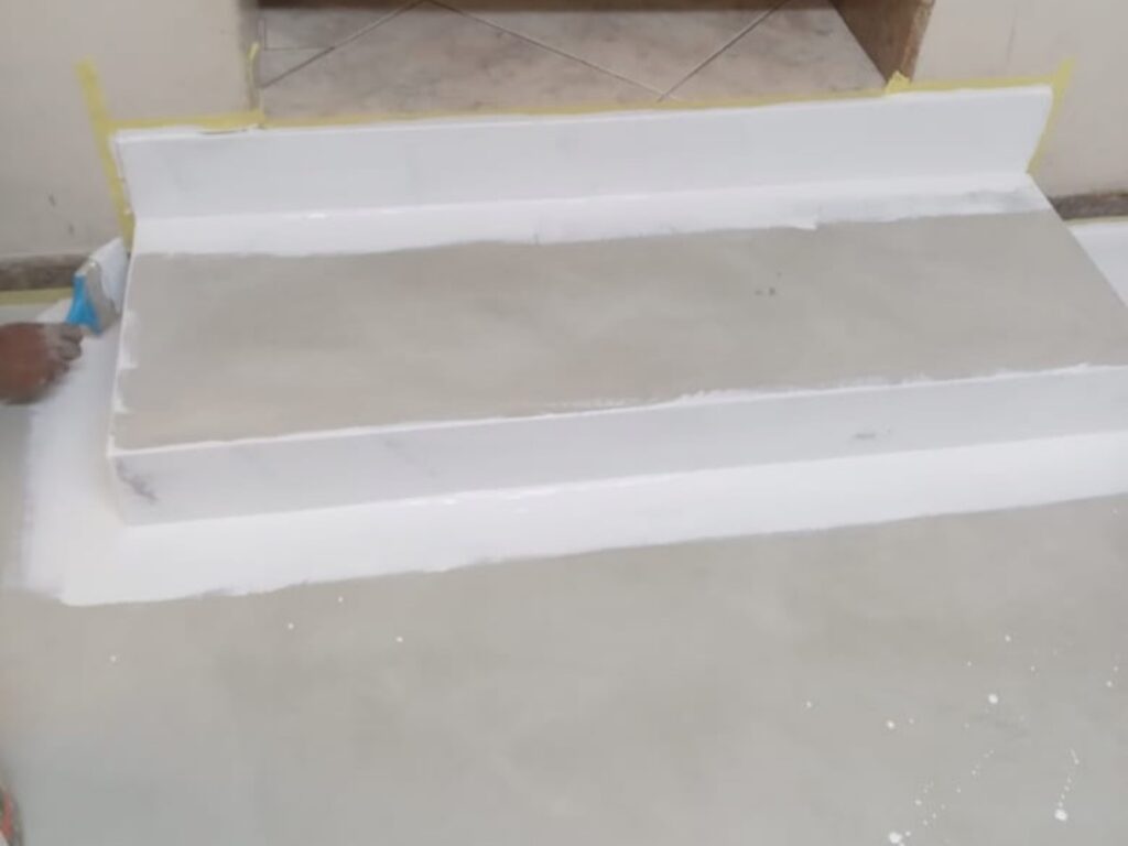 White waterproof coating being built up on a stepped wet area